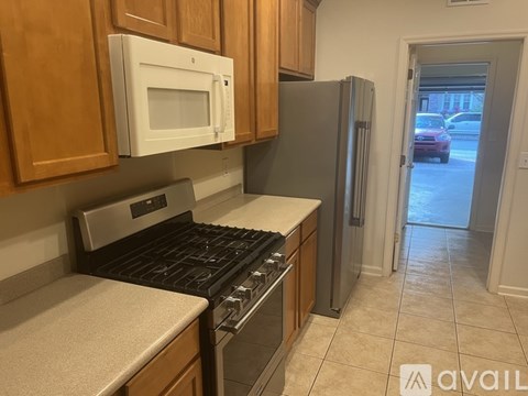 A kitchen with a white microwave above a stove and a silver refrigerator.