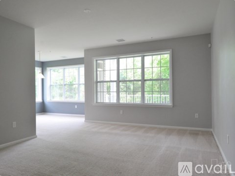A spacious room with large windows and carpeted floor.