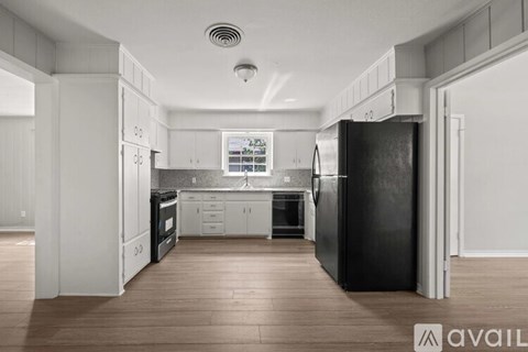 A modern kitchen with white cabinets and a black refrigerator.