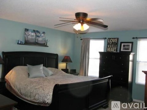 A bedroom with a bed, dresser, and ceiling fan.