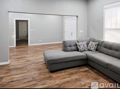 A living room with a grey couch and a wooden floor.