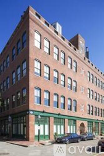 A red brick building with green trim and a white sign with black lettering.