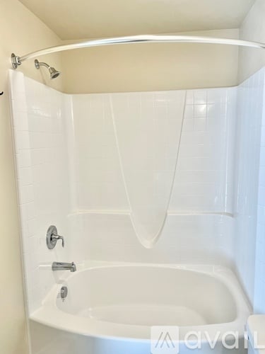 A white bathtub with a shower curtain and a shower head.