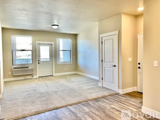 A spacious room with a rug on the floor and a door on the right.