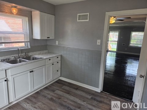 A kitchen with white cabinets and a grey tiled backsplash.