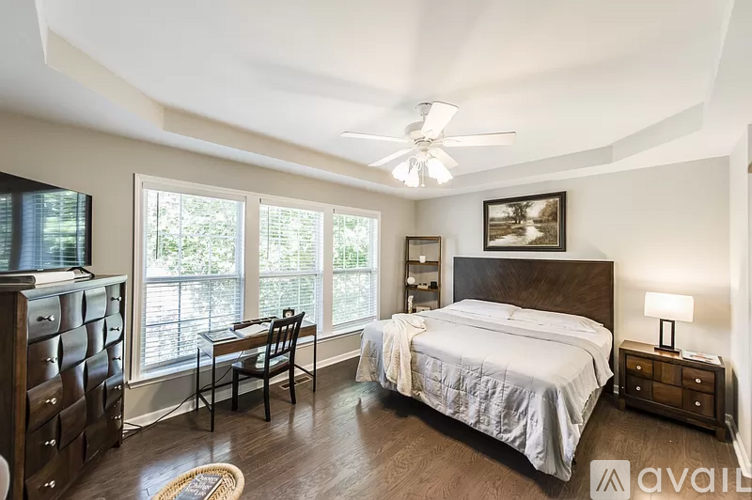 A bedroom with a large bed, a chair, and a ceiling fan.