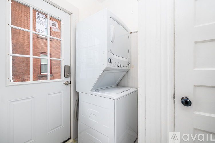 A white washing machine is in a small space between two white doors.