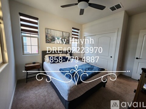 A bedroom with a bed, a ceiling fan, and a painting on the wall.