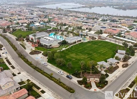 A bird's eye view of a residential area with houses, a swimming pool, and a road.