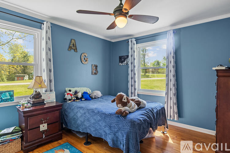 A bedroom with blue walls and a bed with a stuffed animal on it.