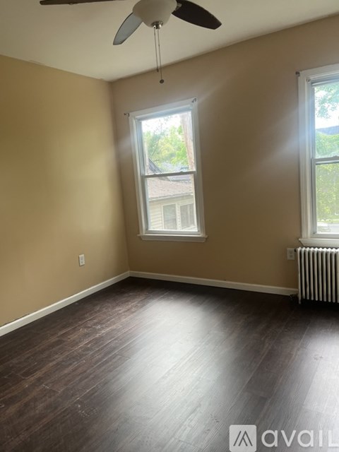 A room with a ceiling fan and two windows.