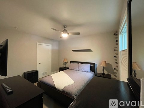 A bedroom with a bed, nightstands, and a ceiling fan.