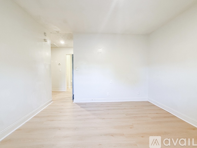 A spacious room with wooden flooring and white walls.