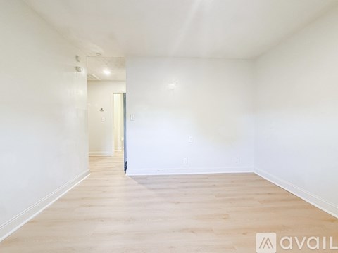 A spacious room with wooden flooring and white walls.