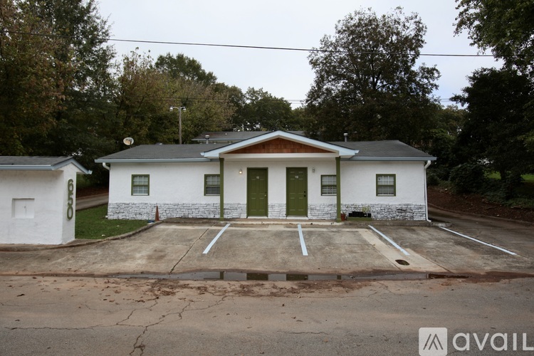 A white house with a green door is surrounded by trees.