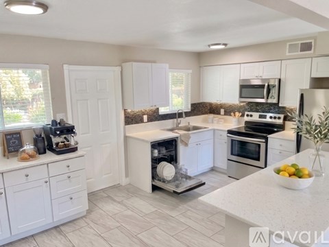 A modern kitchen with white cabinets and appliances.
