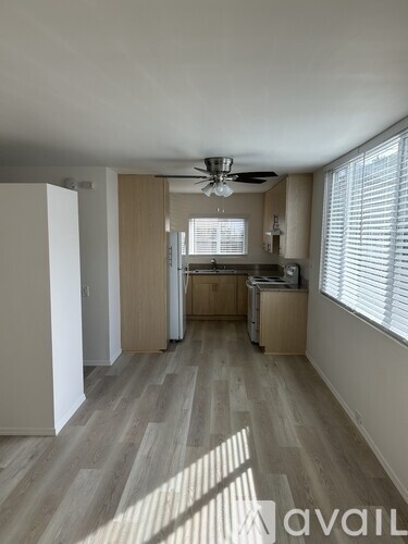 A spacious room with wooden flooring and a ceiling fan.
