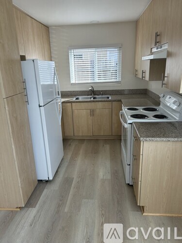 A kitchen with a white fridge, a stove, and wooden cabinets.