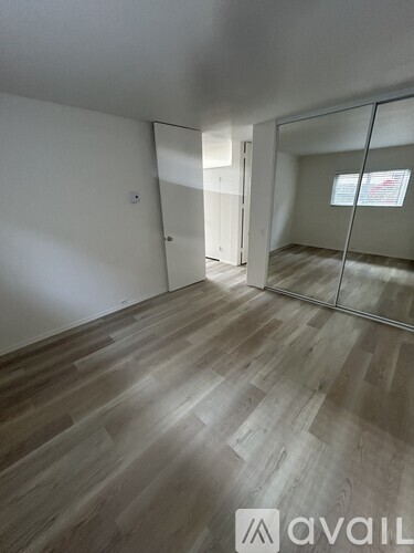 A room with wooden flooring and a glass door leading to another room.