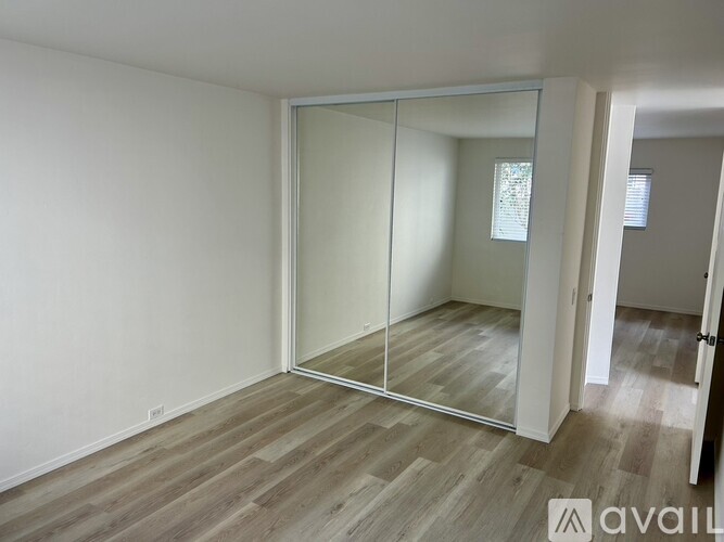 A room with a wooden floor and a large mirror on the wall.