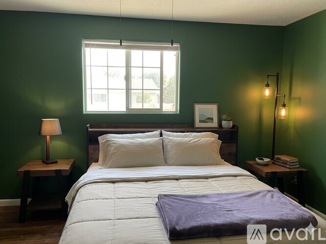 A bedroom with a bed, nightstands, and a window.