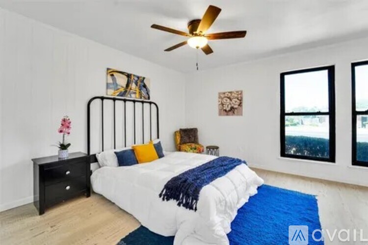 A bedroom with a white bed and a ceiling fan.