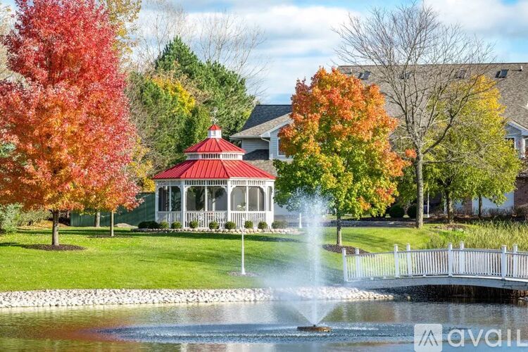 A gazebo is surrounded by trees with autumn leaves.