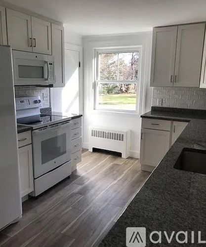 A kitchen with white appliances and wooden floors.