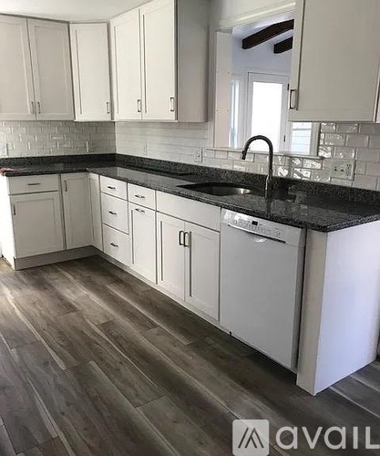 A kitchen with white cabinets and a black countertop.