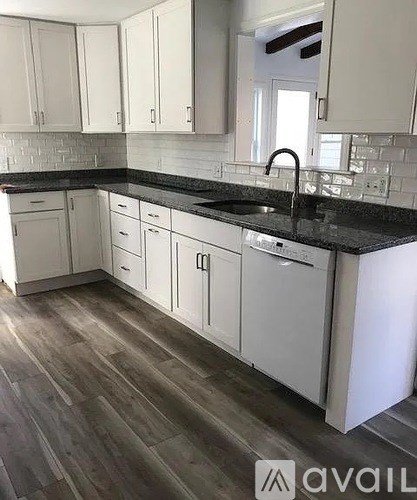 A kitchen with white cabinets and a black countertop.