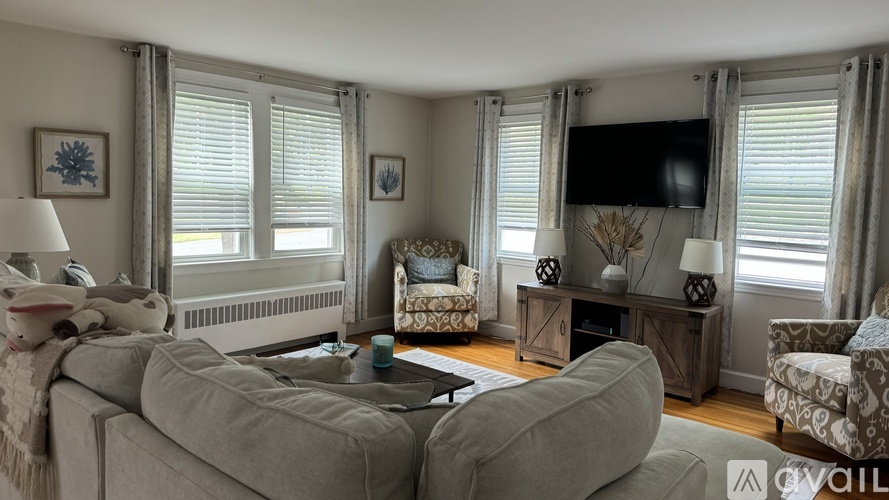 A living room with a grey sofa, a patterned armchair, and a television on a cabinet.