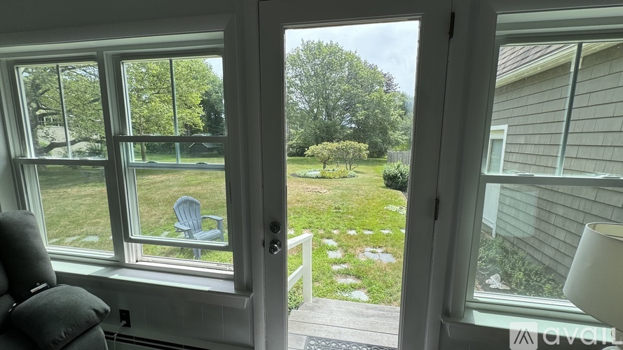 A view from a window looking out to a lawn and trees.