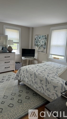 A bedroom with a bed, dresser, and window.