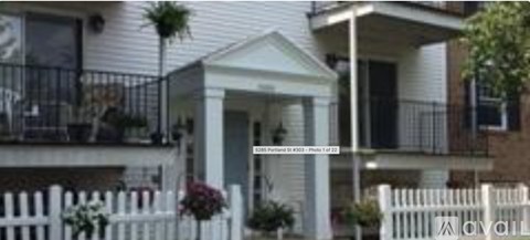 A white house with a black fence and a balcony.