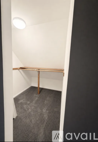 A room with a grey carpet and a wooden bench.