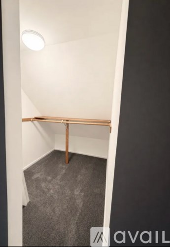 A room with a grey carpet and a wooden bench.