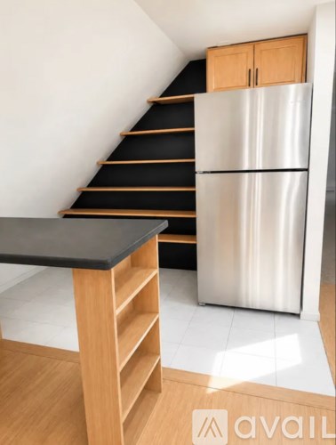 A kitchen with a stainless steel refrigerator and wooden cabinets.