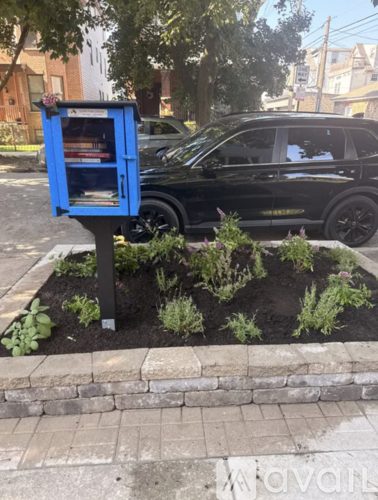 A blue bookcase with books on it is in front of a black car.
