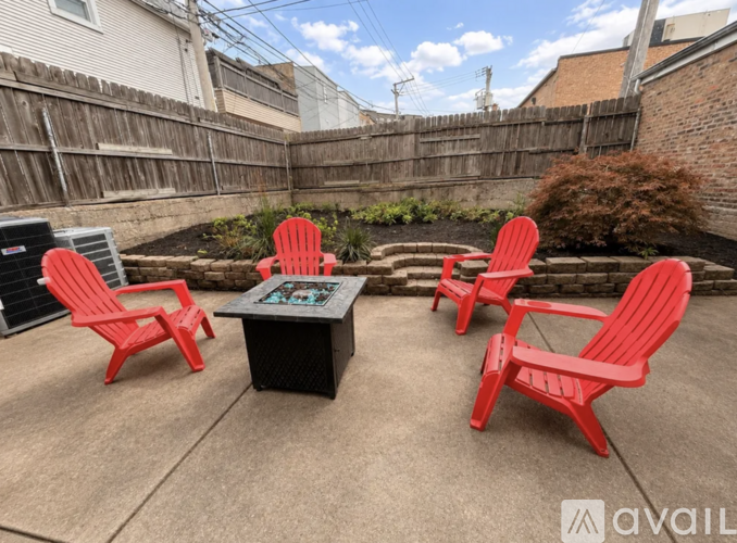 Four red chairs are arranged around a black coffee table in a backyard.
