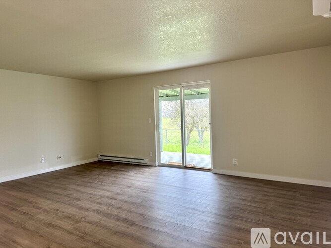 Empty room with wooden floor and sliding glass door.