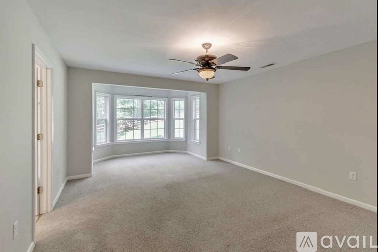A spacious room with a ceiling fan and carpeted floor.