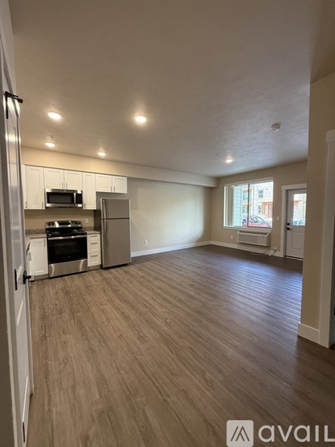 A kitchen with white appliances and wooden flooring.