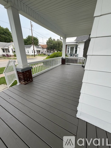 A porch with a white railing and a wooden floor.