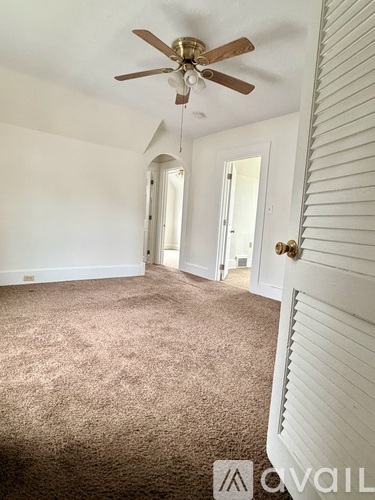 A room with a ceiling fan and carpeted floor.