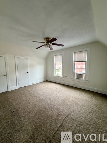 A room with a ceiling fan and carpeted floor.