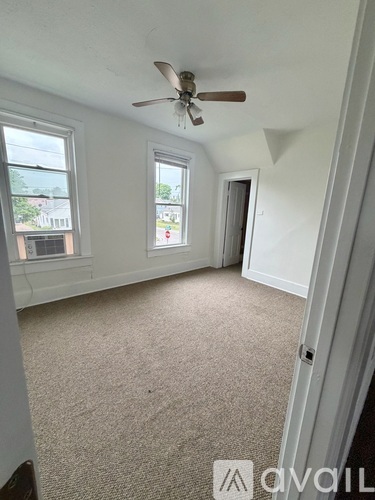 A room with a ceiling fan and carpeted floor.