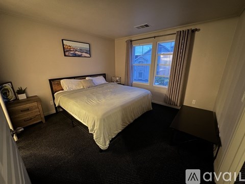 A bedroom with a large bed and a window with curtains.