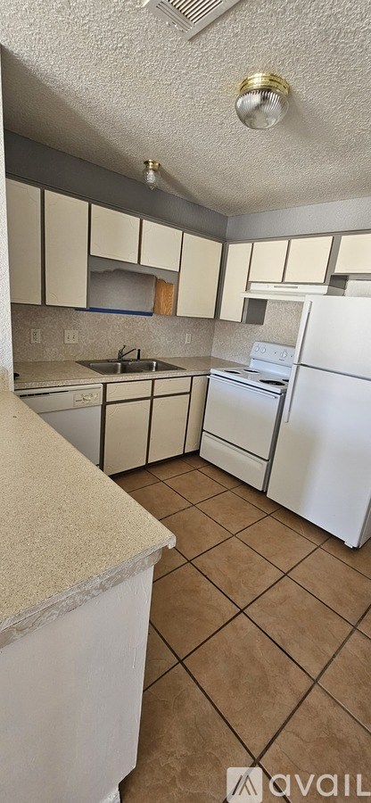 A kitchen with white cabinets and a white refrigerator.