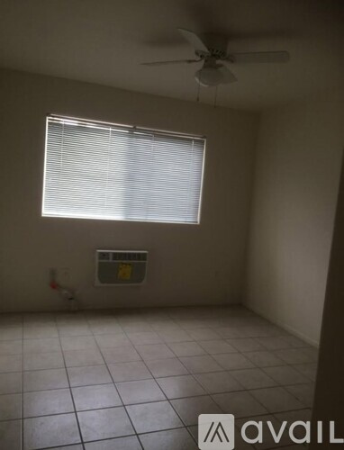 A room with a ceiling fan and a window with blinds.