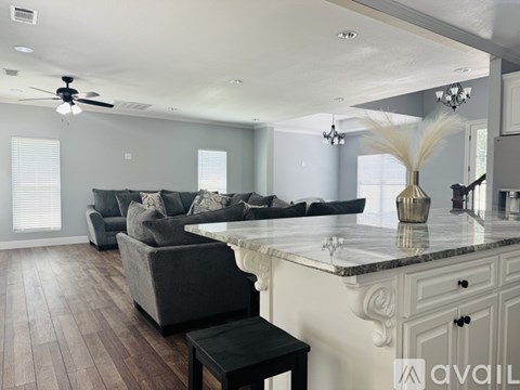 A spacious living room with a grey couch and a marble countertop.